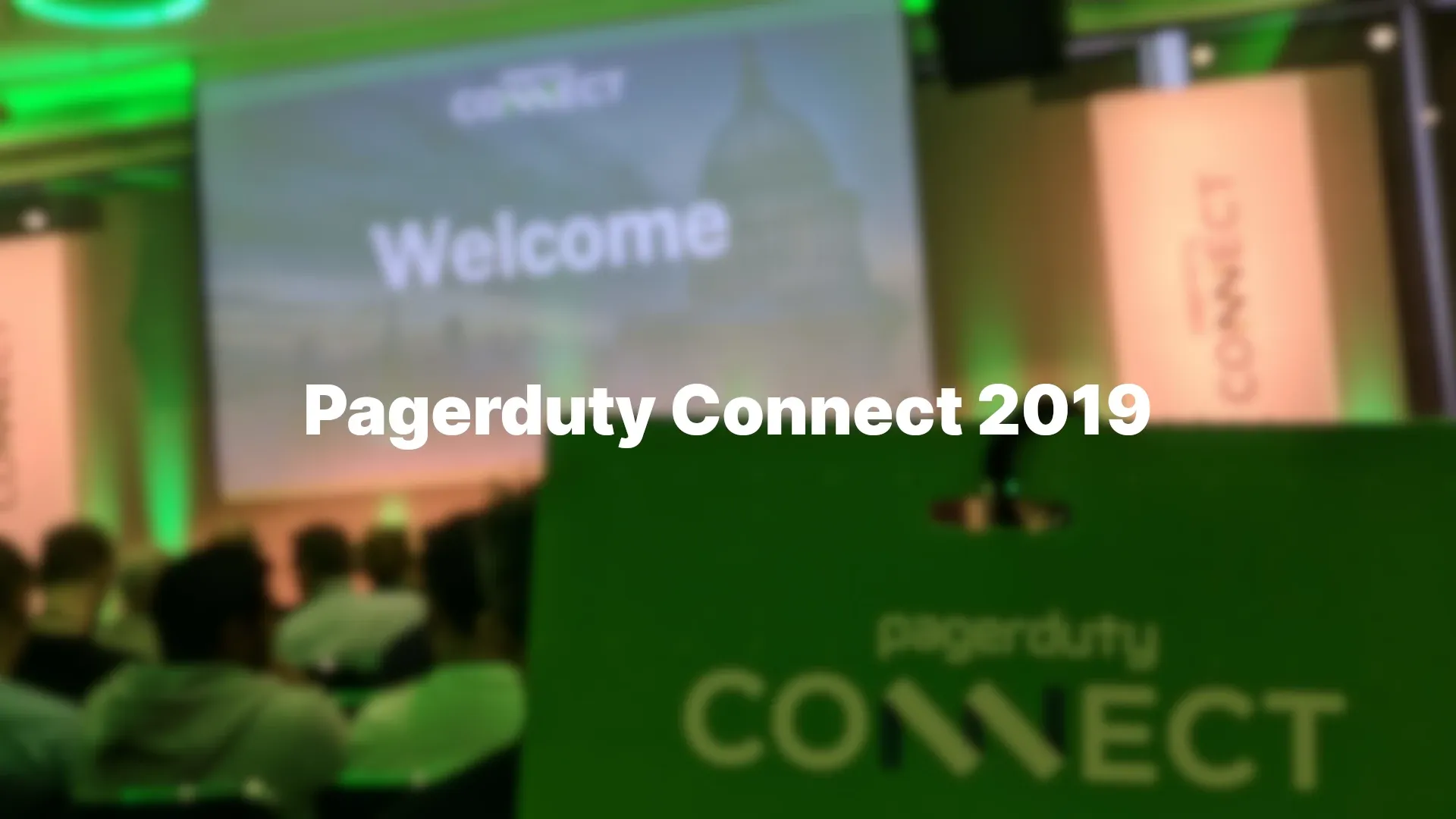 A PagerDuty Connect lanyard and badge in focus, with a 'welcome' presentation behind